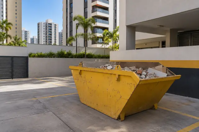 Aluguel de caçamba de entulho DF: caçamba na área de serviço de um condomínio — serviço disponível em Águas Claras. Cena ilustrativa.